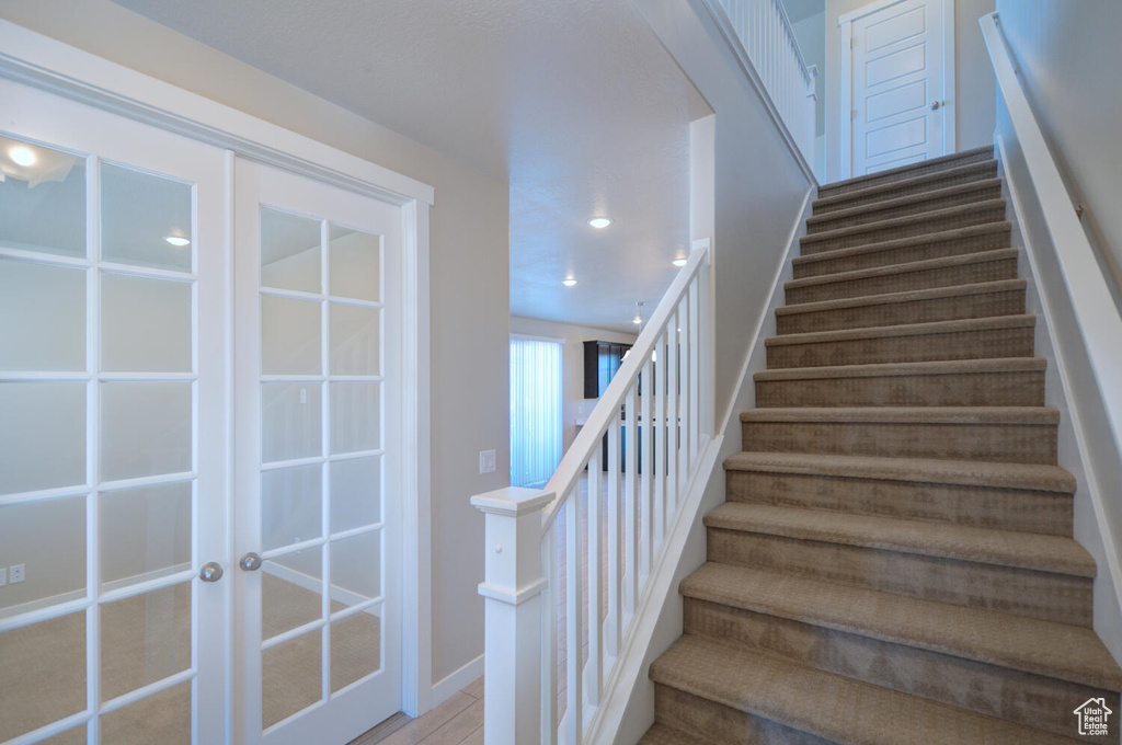 Stairway with french doors and light hardwood / wood-style floors