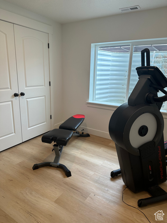 Exercise room with light hardwood / wood-style floors