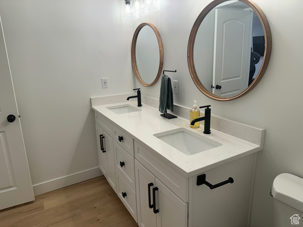 Bathroom featuring toilet, dual vanity, and wood-type flooring