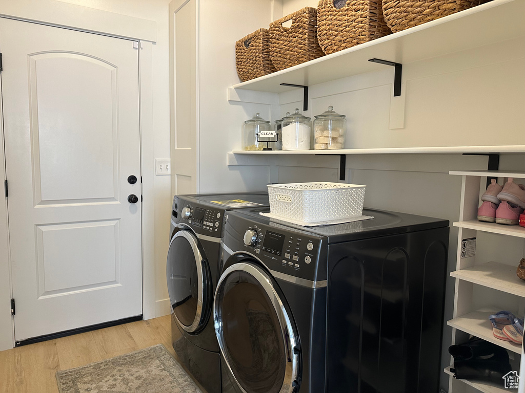 Laundry area with washer and dryer and light hardwood / wood-style flooring
