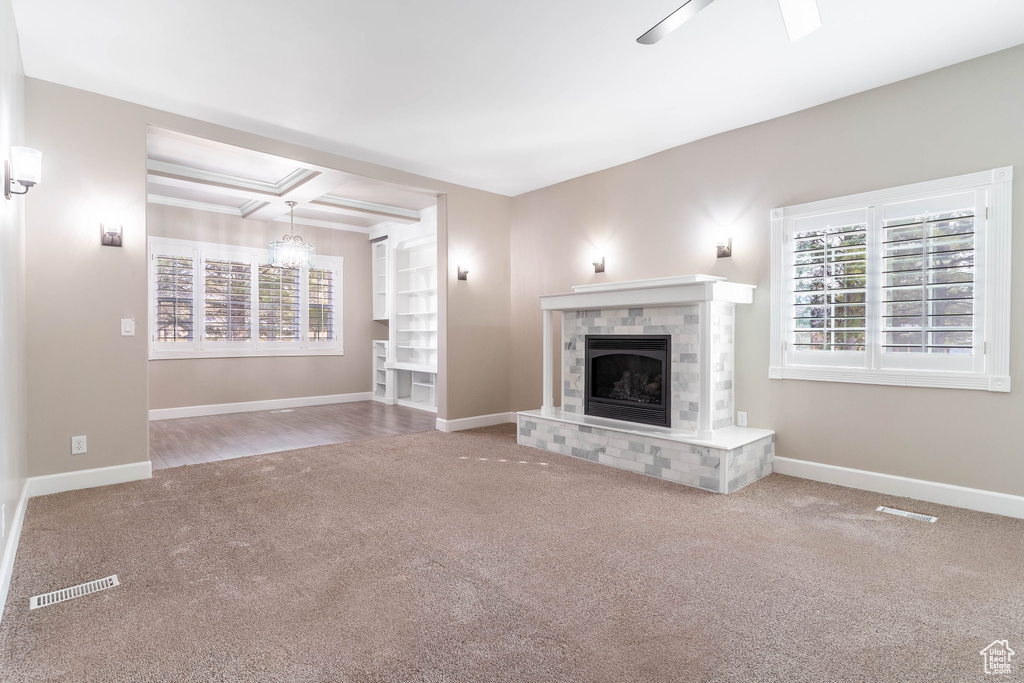 Unfurnished living room with a brick fireplace, coffered ceiling, and carpet