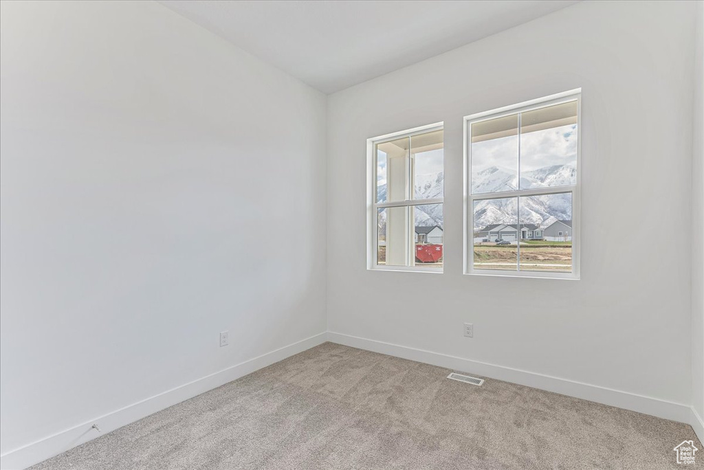 Empty room featuring light colored carpet and a mountain view