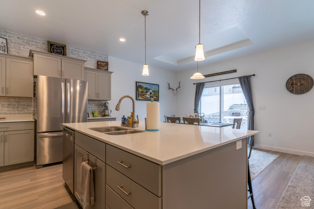 Kitchen with a center island with sink, tasteful backsplash, and light hardwood / wood-style flooring