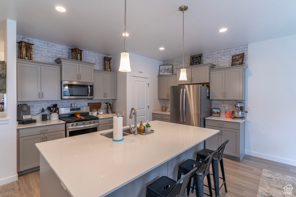 Kitchen featuring a kitchen bar, stainless steel appliances, backsplash, and pendant lighting