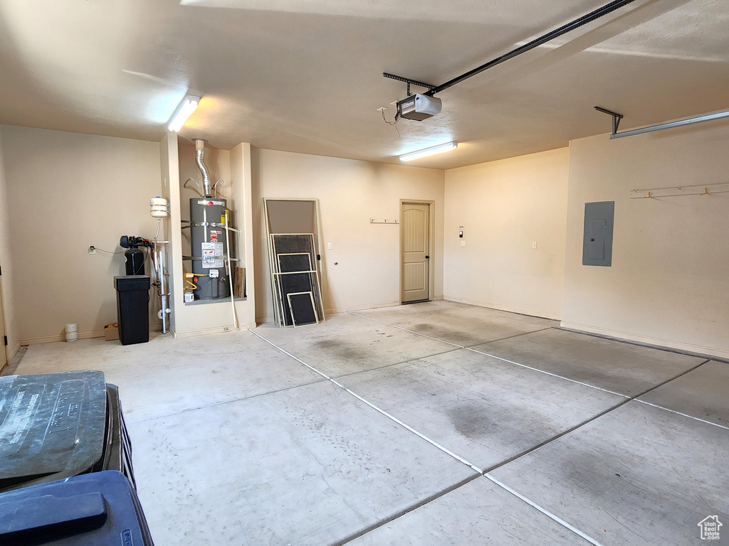 Garage with strapped water heater and a garage door opener