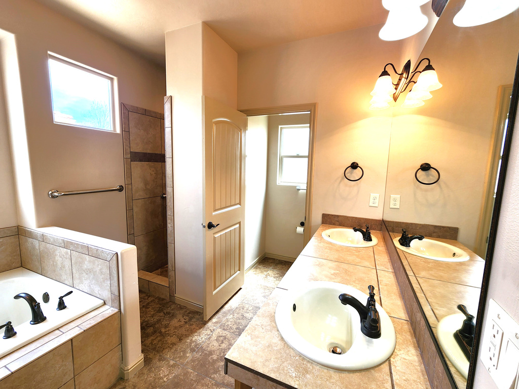 Bathroom featuring oversized vanity, tile floors, dual sinks, and a wealth of natural light