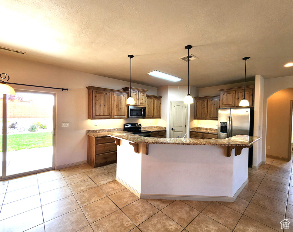 Kitchen with a kitchen breakfast bar, stainless steel appliances, and light tile floors