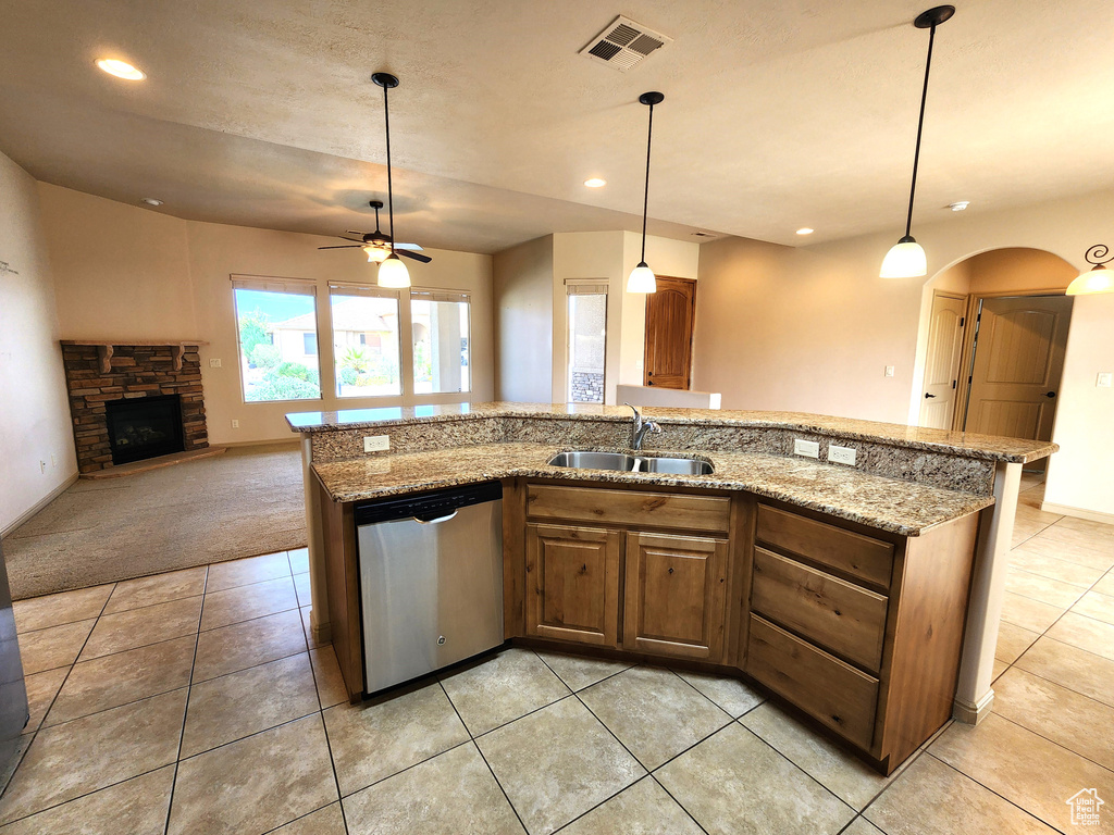 Kitchen with light tile floors, light stone countertops, dishwasher, and a fireplace