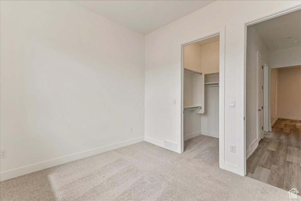 Unfurnished bedroom with a spacious closet, a closet, and light hardwood / wood-style flooring