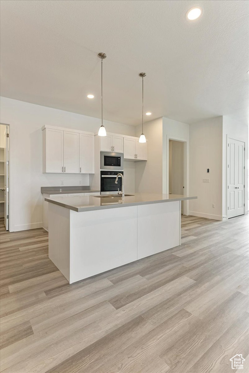 Kitchen with white cabinetry, appliances with stainless steel finishes, and light wood-type flooring