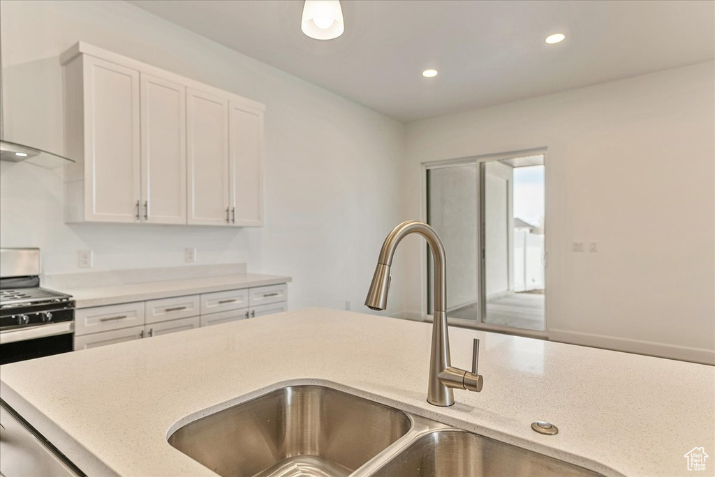 Kitchen with sink, stainless steel range with gas cooktop, premium range hood, and white cabinetry