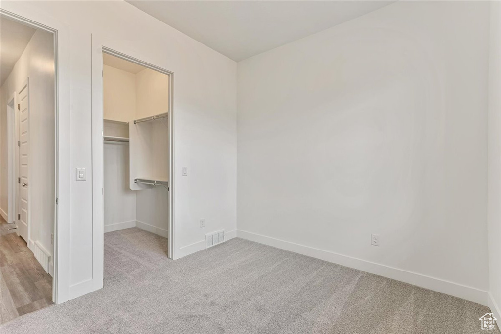 Unfurnished bedroom with a spacious closet, light hardwood / wood-style floors, and a closet