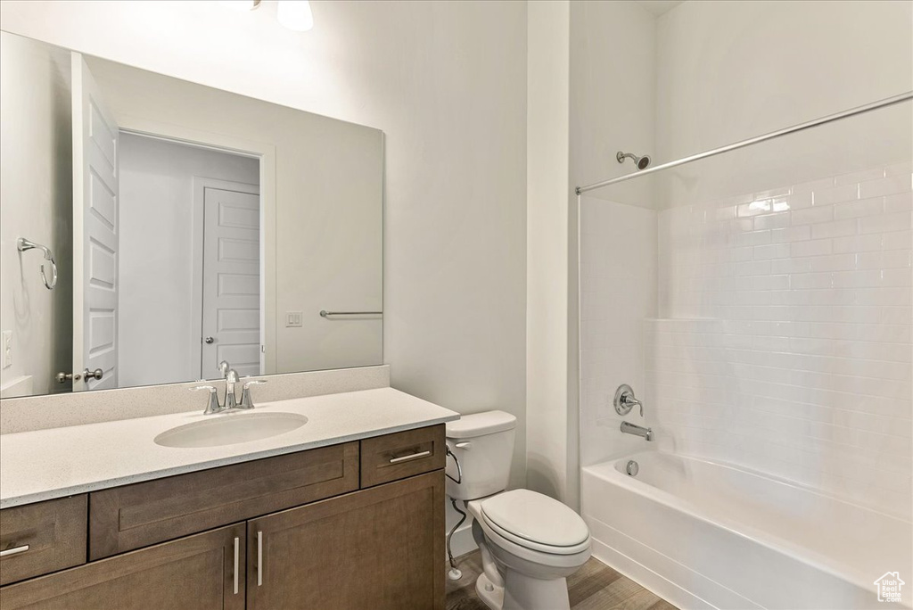 Full bathroom with toilet, large vanity, hardwood / wood-style flooring, and tub / shower combination