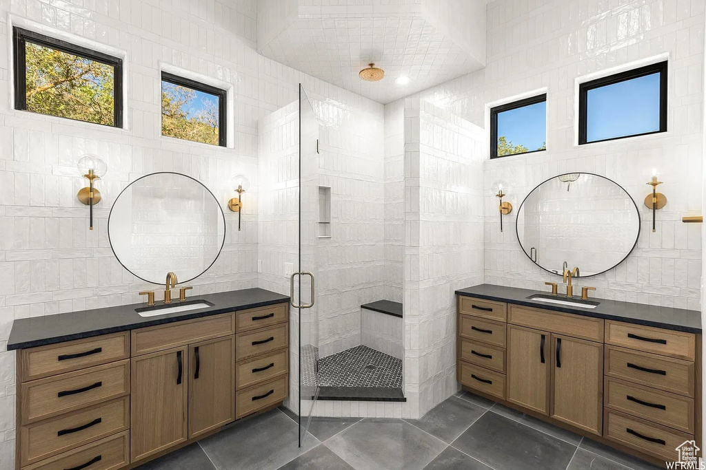 Bathroom featuring a shower with door, tile flooring, and tile walls
