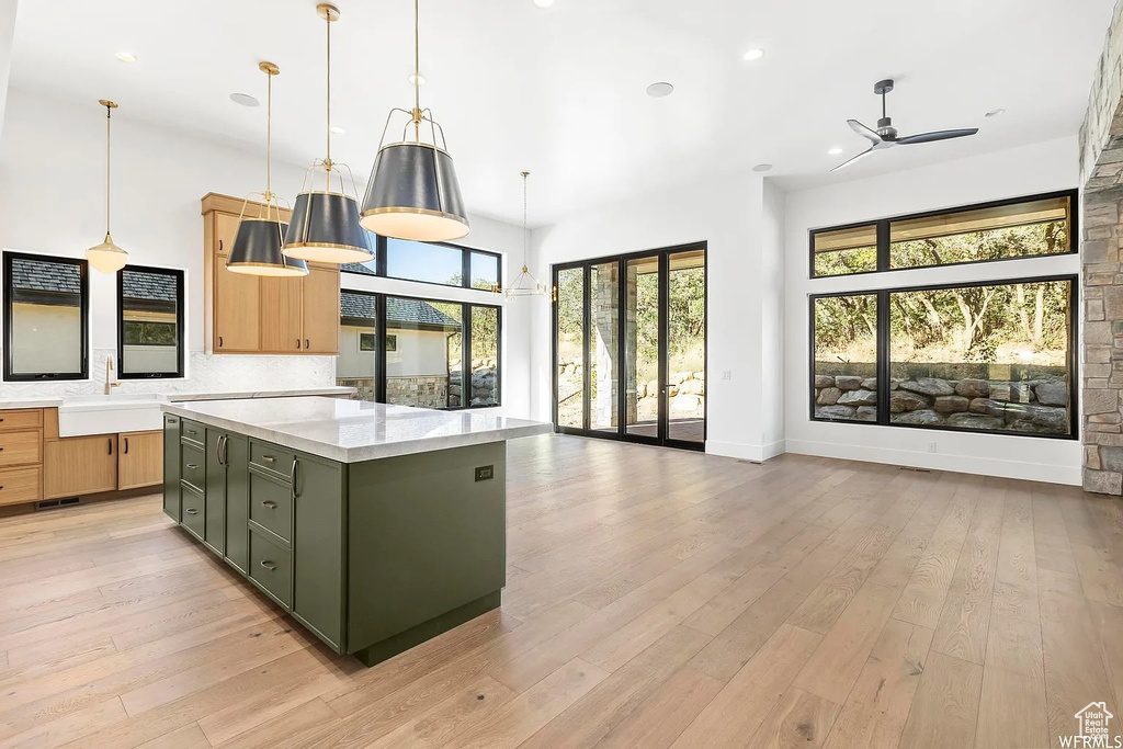 Kitchen featuring decorative light fixtures, ceiling fan, green cabinets, and light wood-type flooring