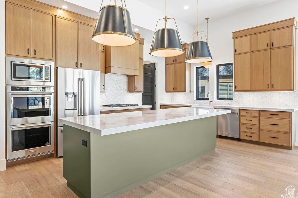 Kitchen with backsplash, a kitchen island, stainless steel appliances, and pendant lighting