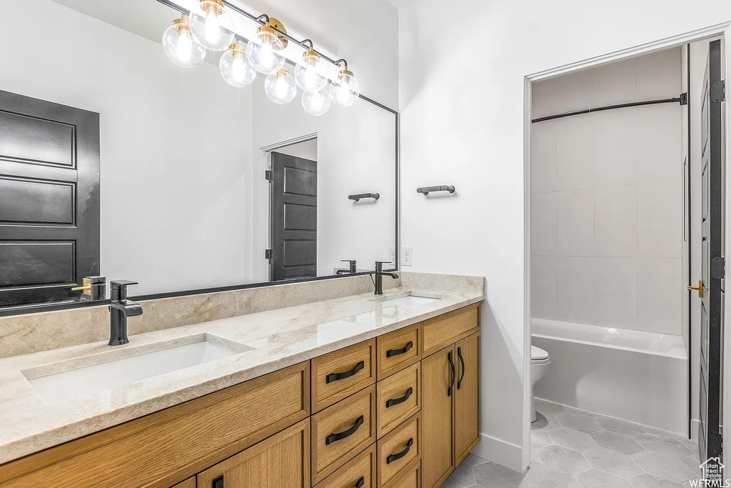 Full bathroom featuring tile floors, washtub / shower combination, double sink, toilet, and vanity with extensive cabinet space