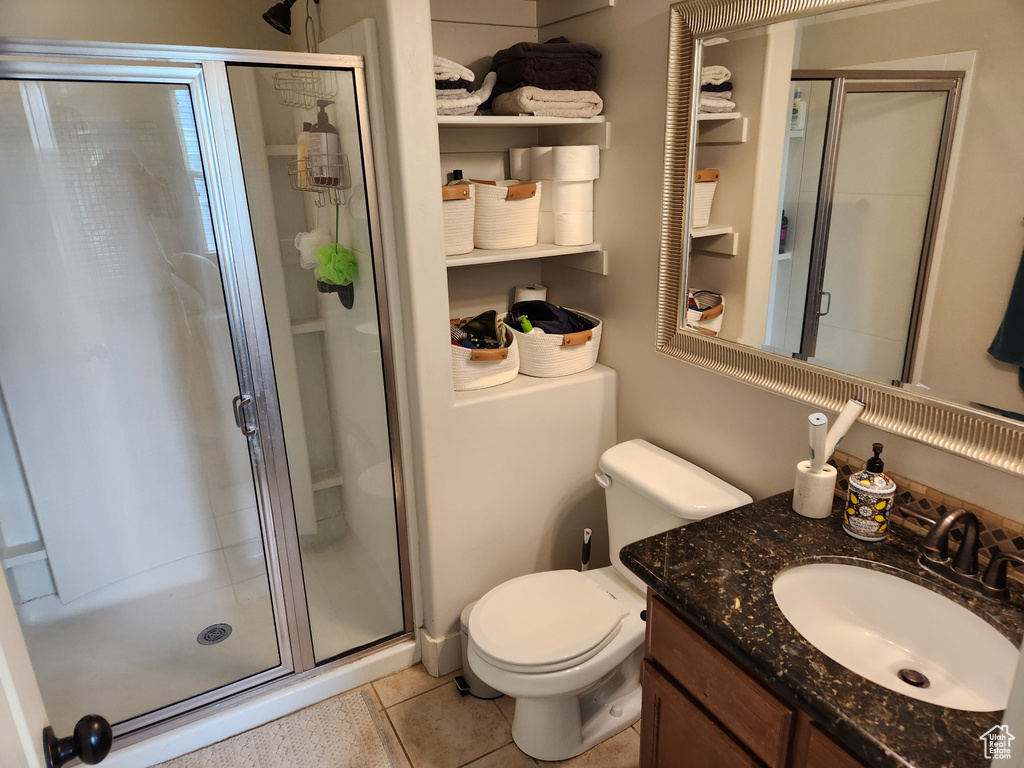 Bathroom featuring tile floors, an enclosed shower, toilet, and vanity