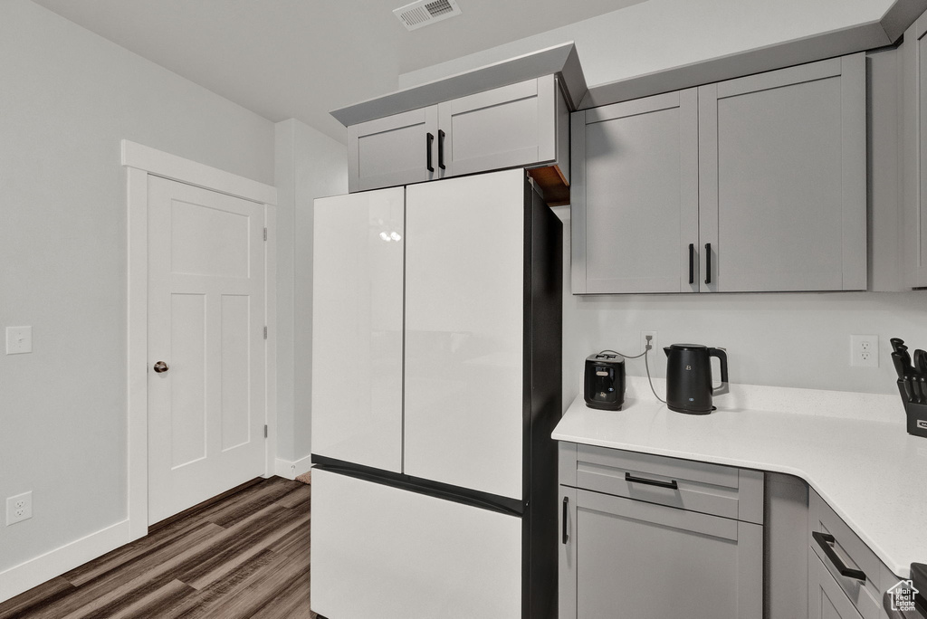 Kitchen featuring gray cabinetry, white refrigerator, and dark hardwood / wood-style flooring