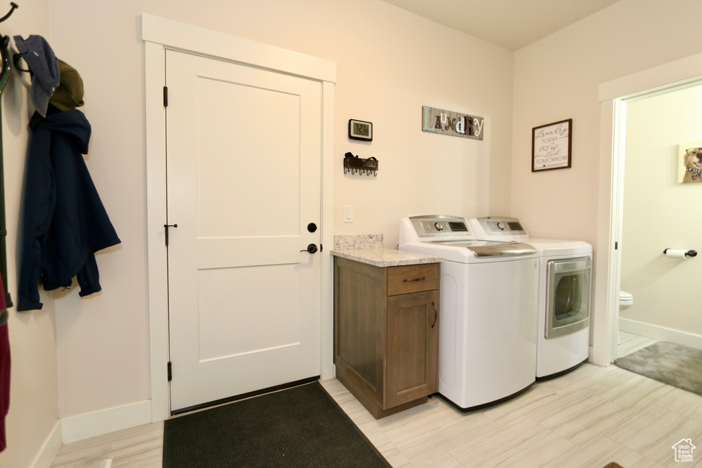 Washroom featuring cabinets and washing machine and clothes dryer