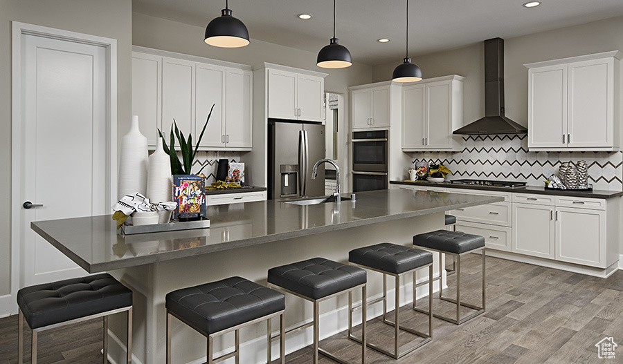Kitchen with appliances with stainless steel finishes, pendant lighting, wall chimney exhaust hood, backsplash, and sink