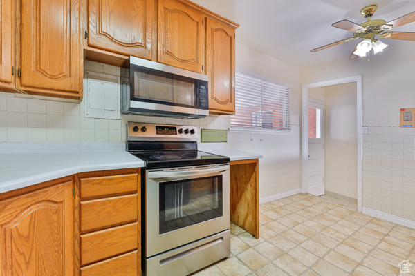 Kitchen with ceiling fan, backsplash, appliances with stainless steel finishes, and light tile floors