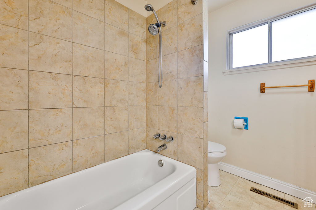 Bathroom featuring tiled shower / bath combo, tile flooring, and toilet