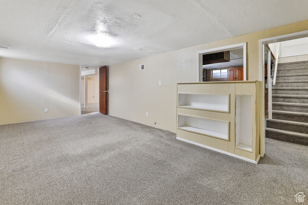 Basement featuring carpet flooring and a textured ceiling