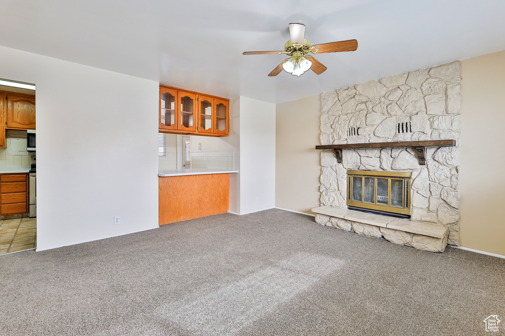 Unfurnished living room with carpet flooring, ceiling fan, and a fireplace