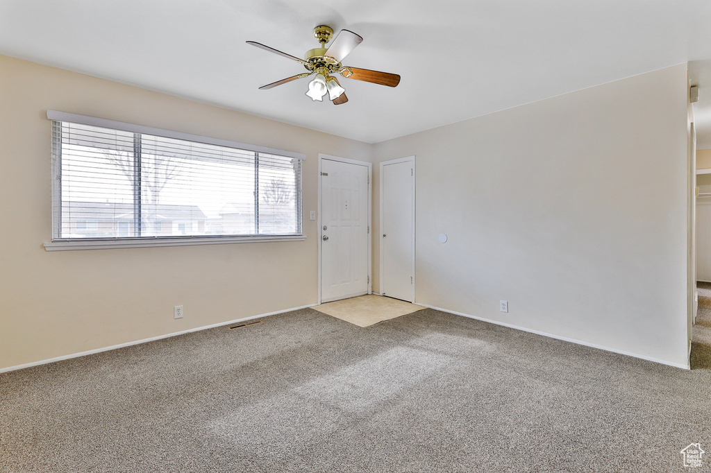 Unfurnished room with ceiling fan, light carpet, and a healthy amount of sunlight