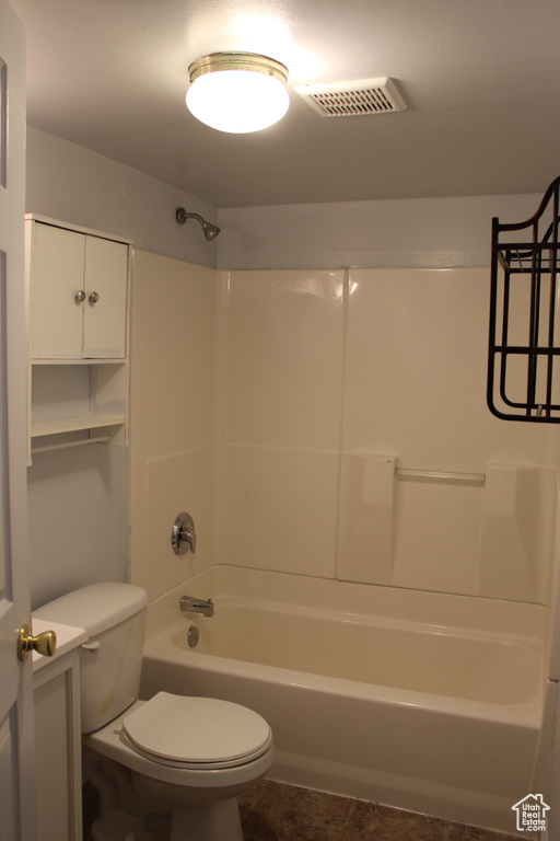 Bathroom with tile flooring, shower / washtub combination, and toilet