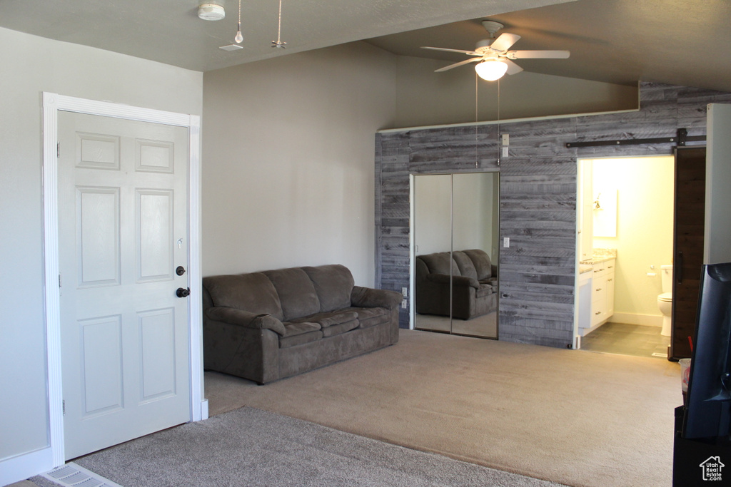 Sitting room with light carpet, a barn door, ceiling fan, and lofted ceiling