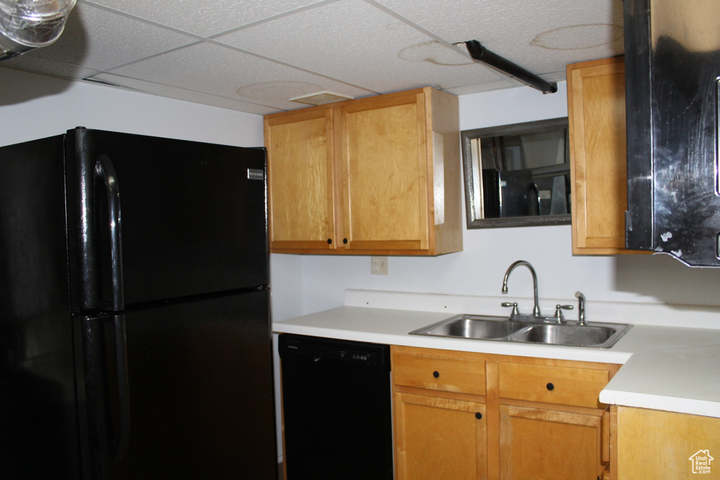 Kitchen with a drop ceiling, black appliances, and sink