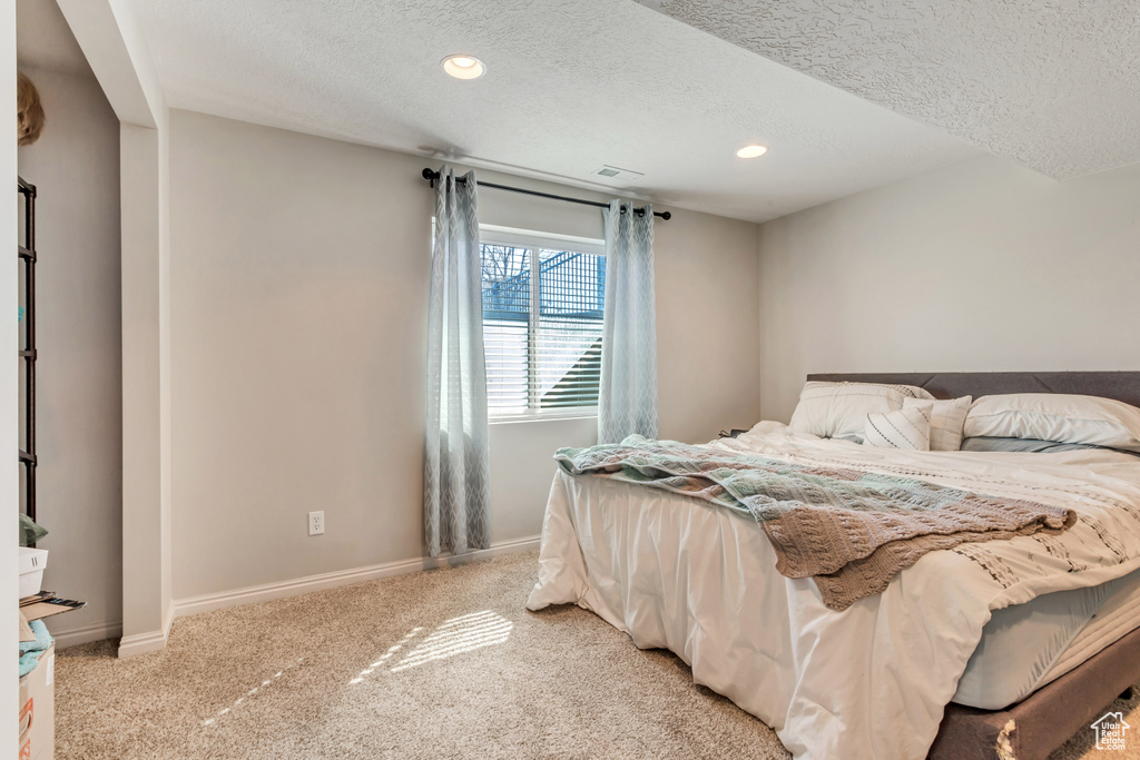 Bedroom featuring a textured ceiling and light colored carpet