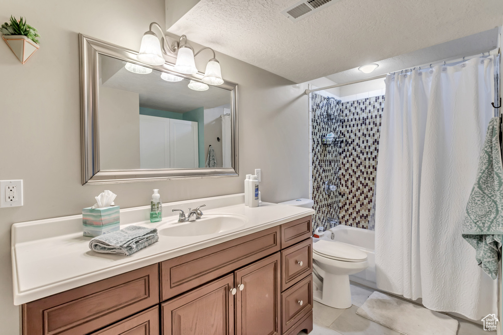 Full bathroom featuring shower / tub combo, oversized vanity, a textured ceiling, toilet, and tile floors