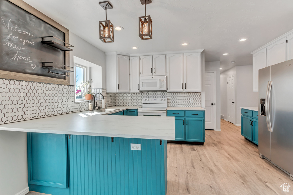 Kitchen featuring hanging light fixtures, white cabinets, light hardwood / wood-style flooring, white appliances, and tasteful backsplash