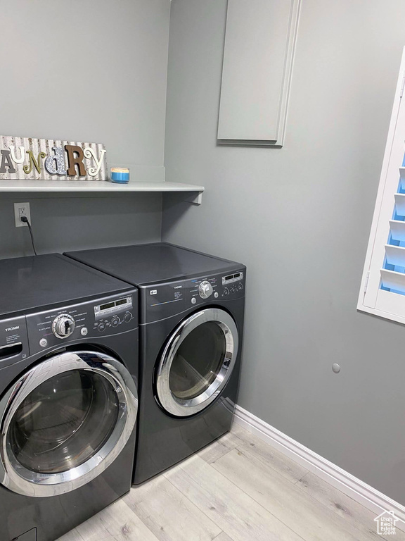 Laundry room with separate washer and dryer and light hardwood / wood-style floors