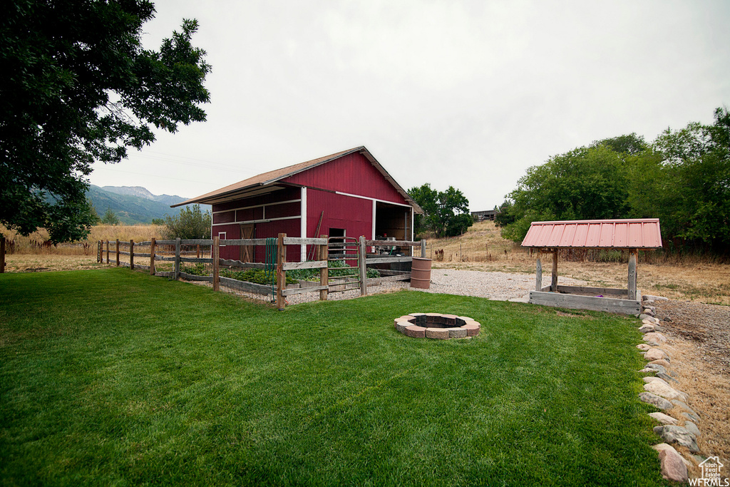 View of yard with a rural view, a mountain view, an outdoor structure, and a fire pit