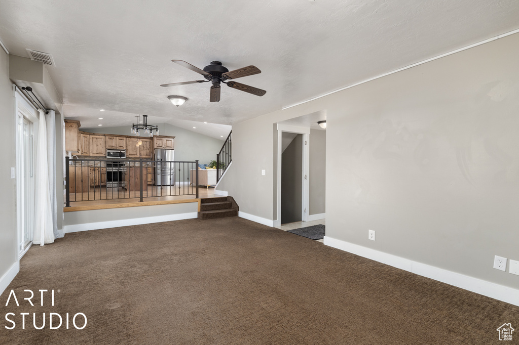 Unfurnished living room with ceiling fan, lofted ceiling, and dark colored carpet