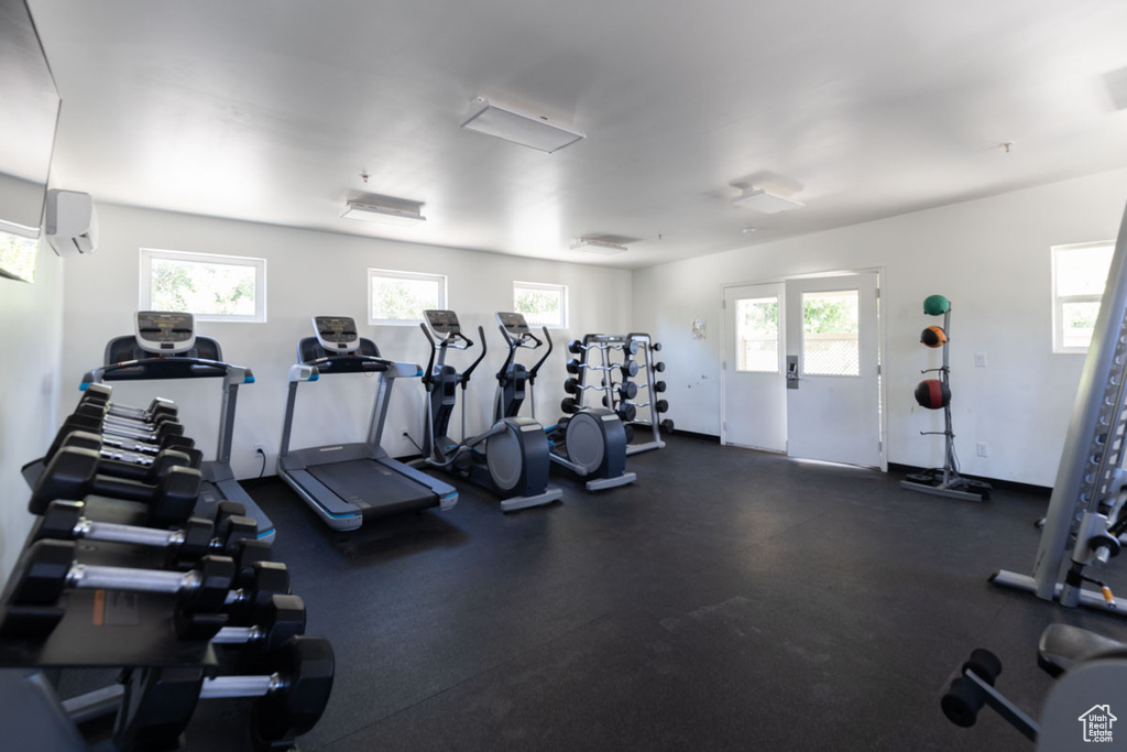 Exercise room featuring an AC wall unit and plenty of natural light