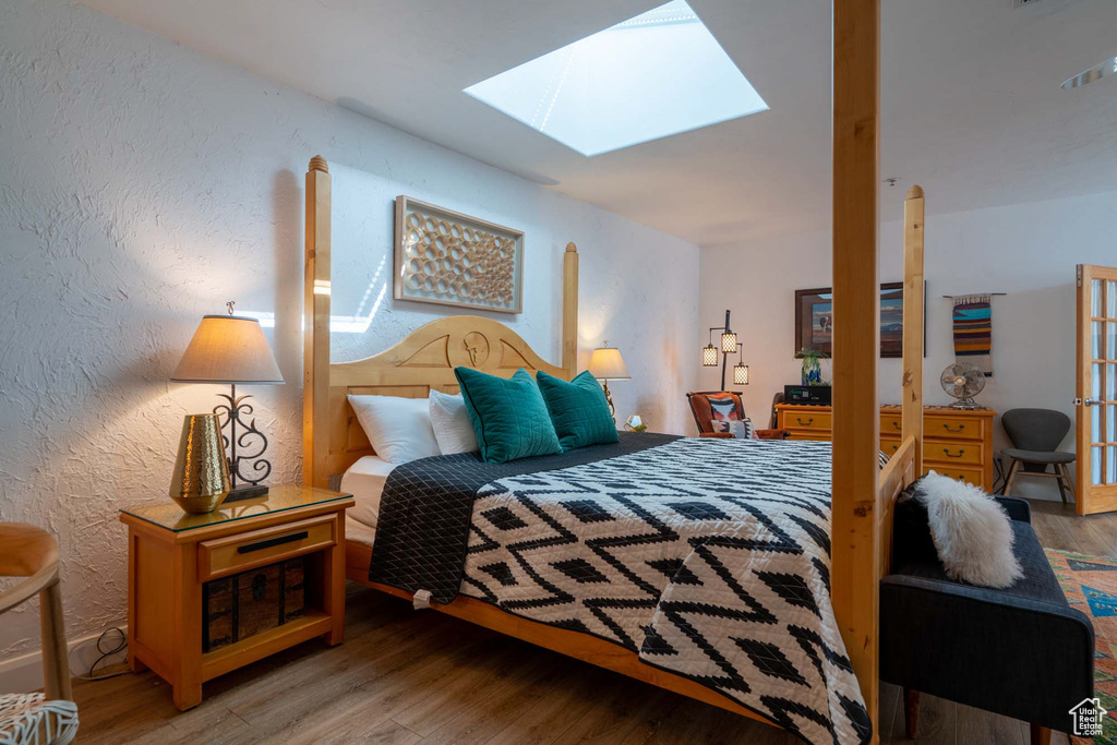 Bedroom with hardwood / wood-style floors and a skylight