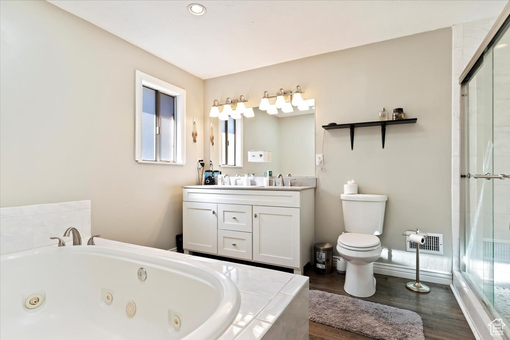 Bathroom featuring toilet, vanity with extensive cabinet space, dual sinks, and wood-type flooring