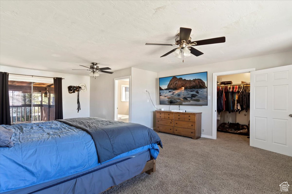 Carpeted bedroom with a closet, ensuite bathroom, access to exterior, ceiling fan, and a walk in closet