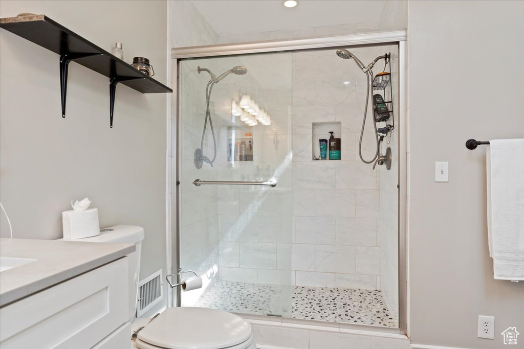 Bathroom featuring a shower with shower door, toilet, and vanity