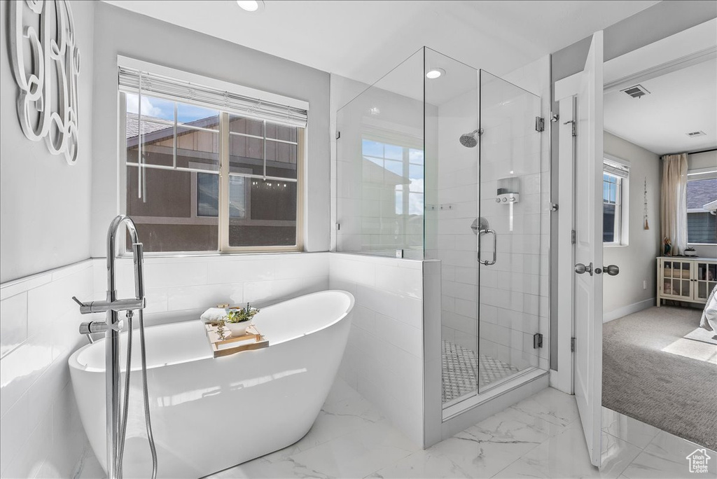 Bathroom featuring plenty of natural light, tile flooring, and tile walls