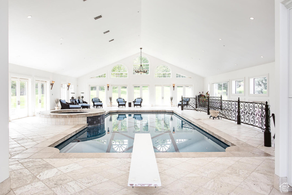 View of pool with a notable chandelier, a diving board, and an indoor hot tub