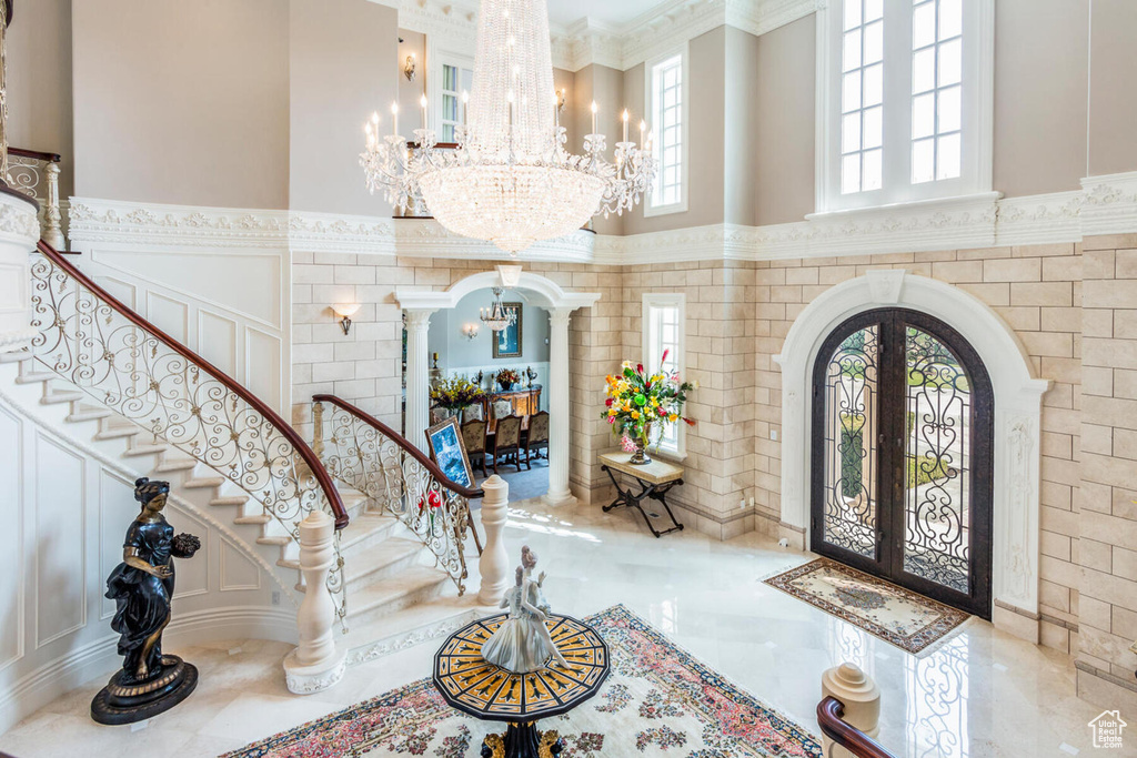 Entrance foyer featuring tile walls, light tile floors, french doors, and an inviting chandelier