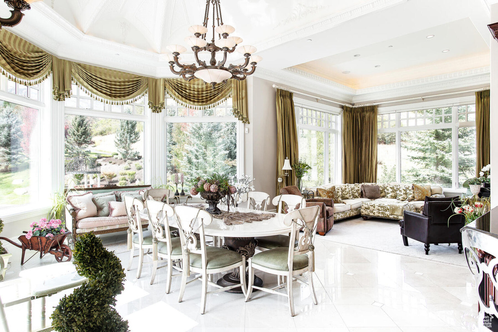 Tiled dining room with a raised ceiling, an inviting chandelier, crown molding, and a wealth of natural light