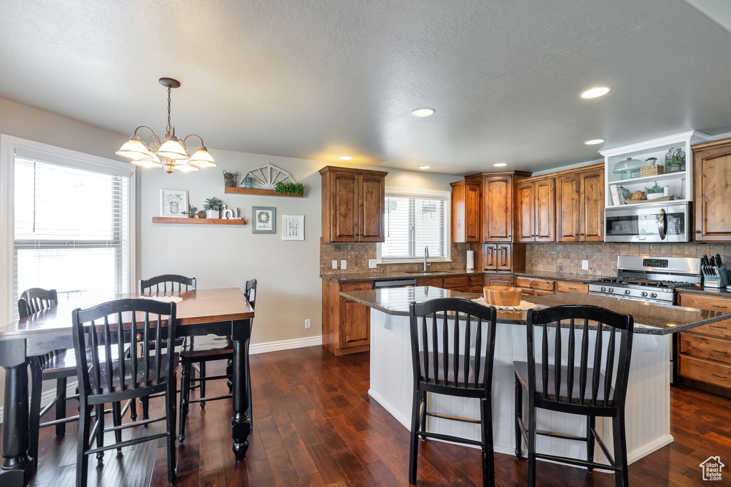 Kitchen featuring a chandelier, stainless steel appliances, decorative light fixtures, a center island, and dark hardwood / wood-style floors