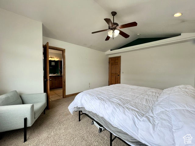 Bedroom with connected bathroom, ceiling fan, vaulted ceiling, and light colored carpet